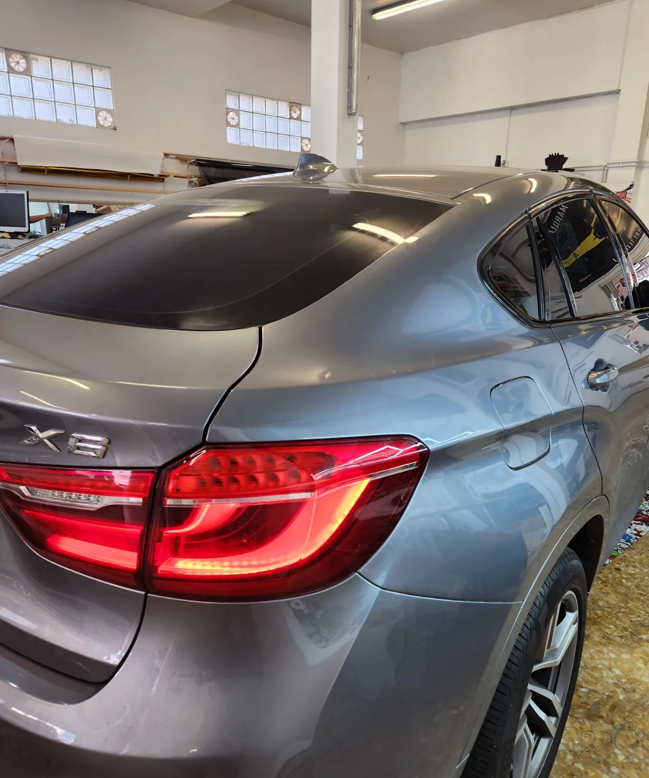 Détail de la lunette arrière et du vitrage latéral teintés sur un BMW X6 gris dans l’atelier Xpert Teinte.
