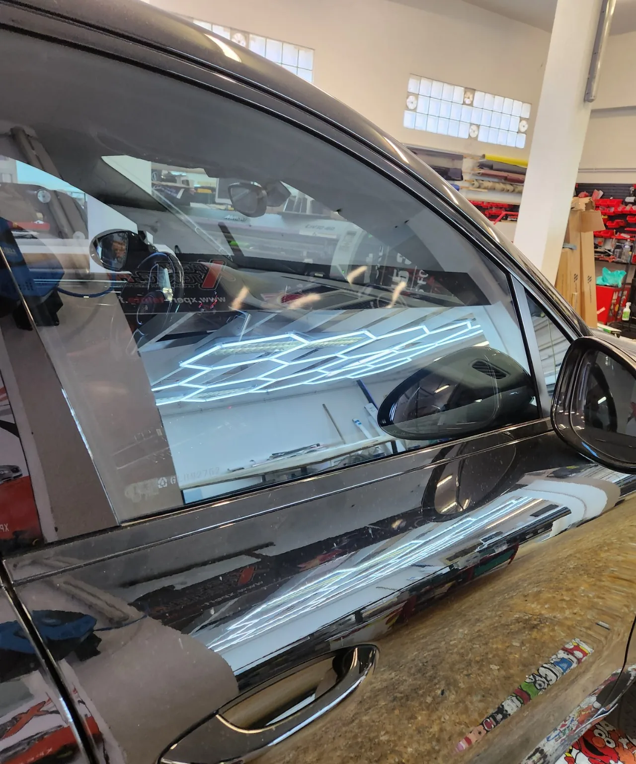 Gros plan sur une vitre latérale et son contour de porte sur un Mercedes noir dans l’atelier Xpert Teinte.