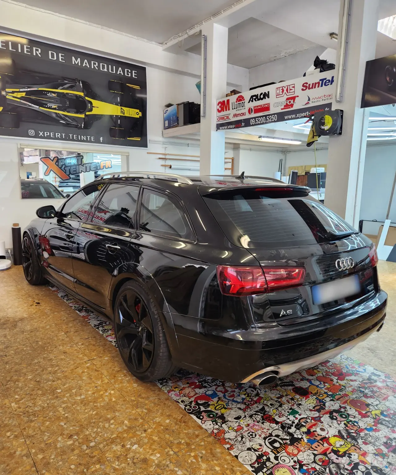 Audi A6 Avant noire vue de trois quarts arrière, avec vitres teintées et lunette arrière visible, dans l’atelier de Toulon.