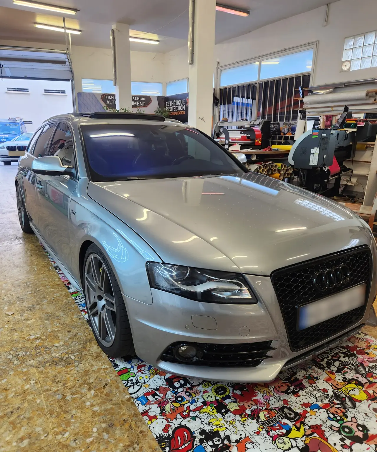 Audi grise vue de trois quarts avant, avec reflets bleutés sur le pare-brise, dans l’atelier Xpert Teinte à Toulon.